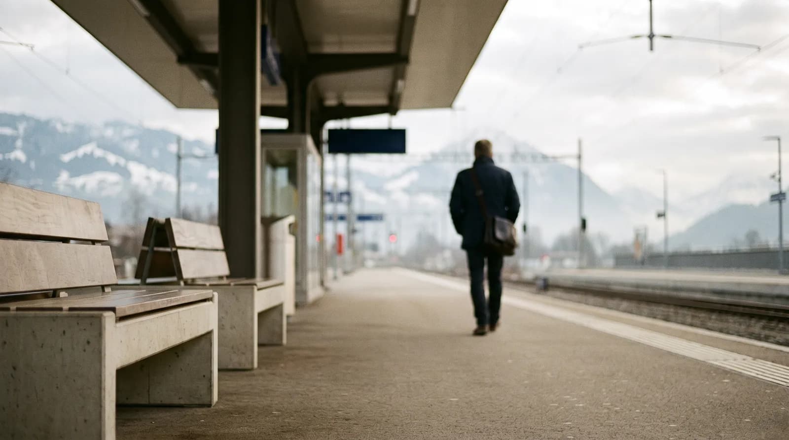 Quai de gare suisse au petit matin, un frontalier de dos